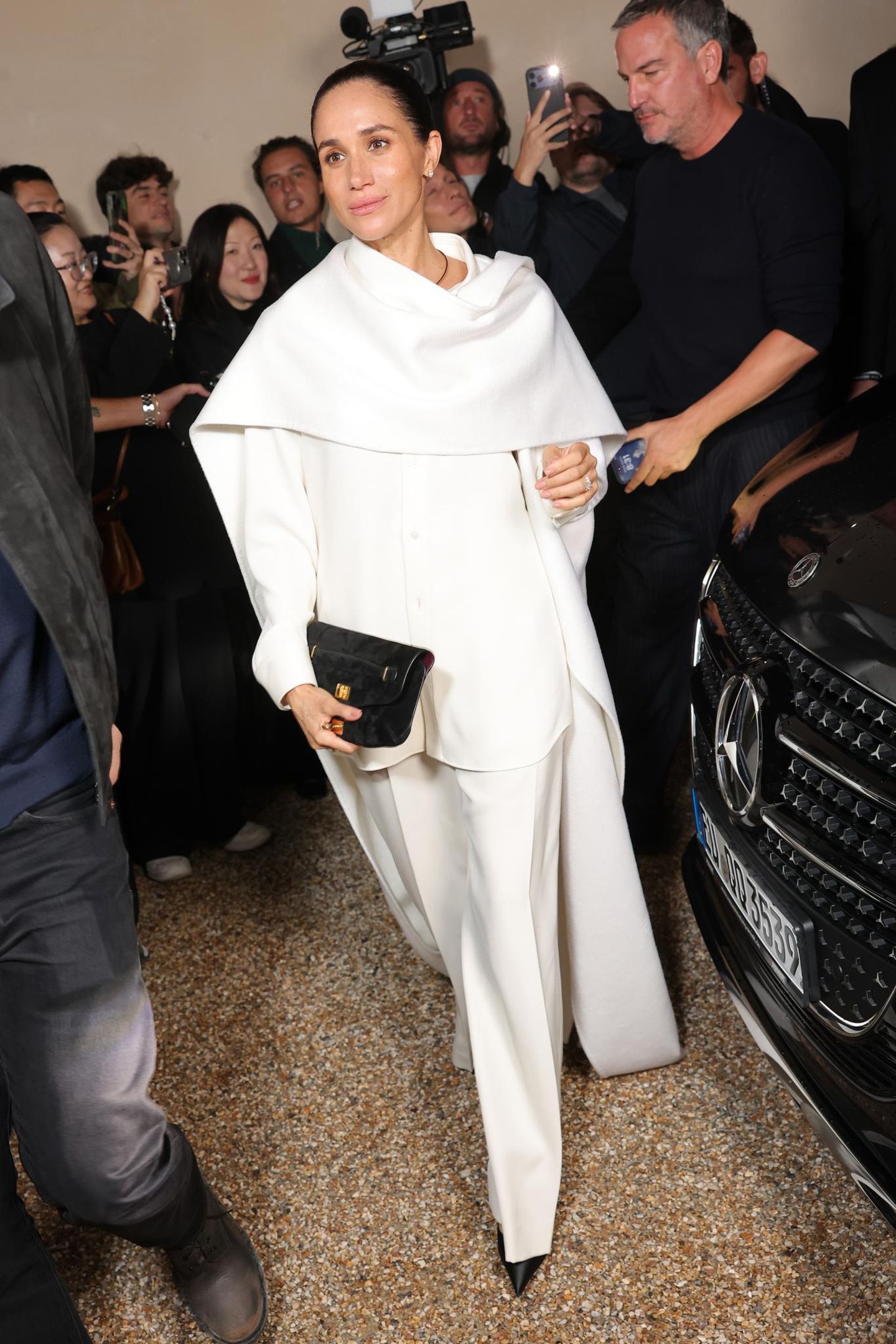 Herzogin Meghan in einem weißen Oberteil, Cape und Hose in Paris