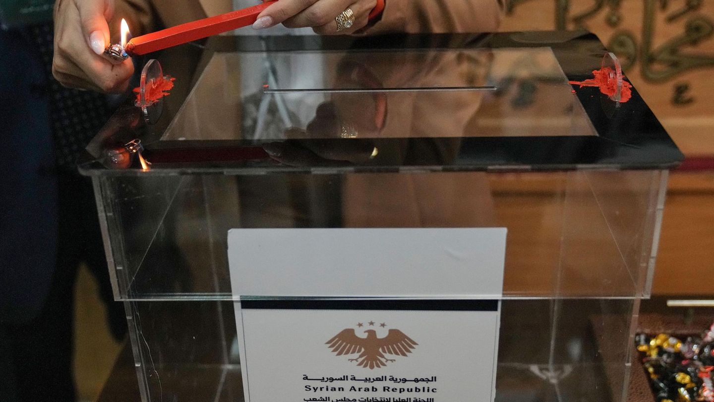 Latakia, Syrien. Eine syrische Wahlhelferin verbrennt das rote Wachs einer Kerze, um eine Wahlurne vor den Parlamentswahlen im Wahllokal des Gouverneurs von Latakia ordnungsgemäß zu versiegeln und dadurch mögliche Manipulationen zu erschweren