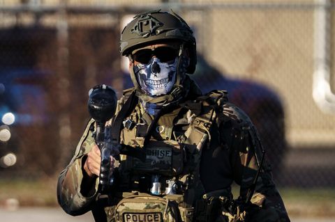 Vollausgerüsteter ICE-Agent, der sein Gesicht mit einem Tuch mit einem Totenkopf bedeckt hat