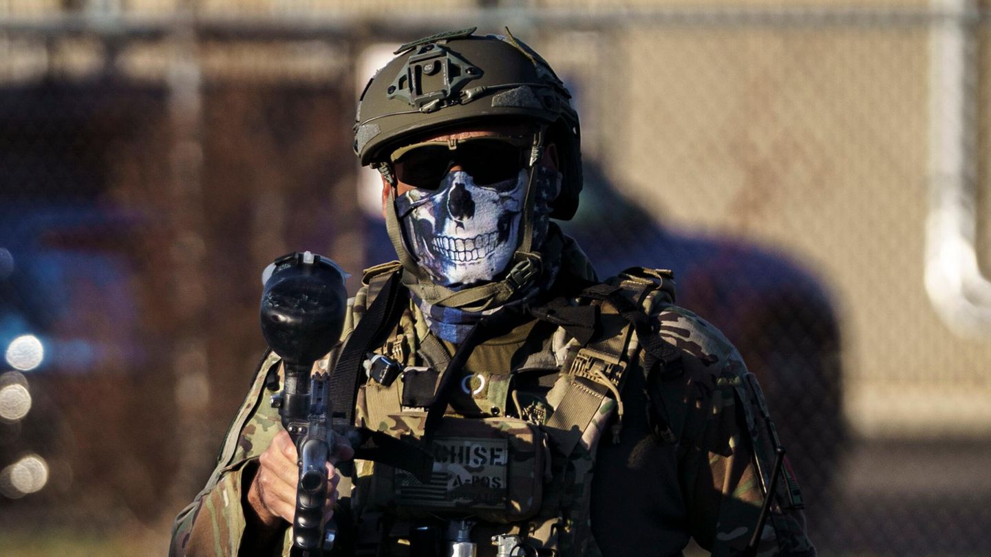 Vollausgerüsteter ICE-Agent, der sein Gesicht mit einem Tuch mit einem Totenkopf bedeckt hat