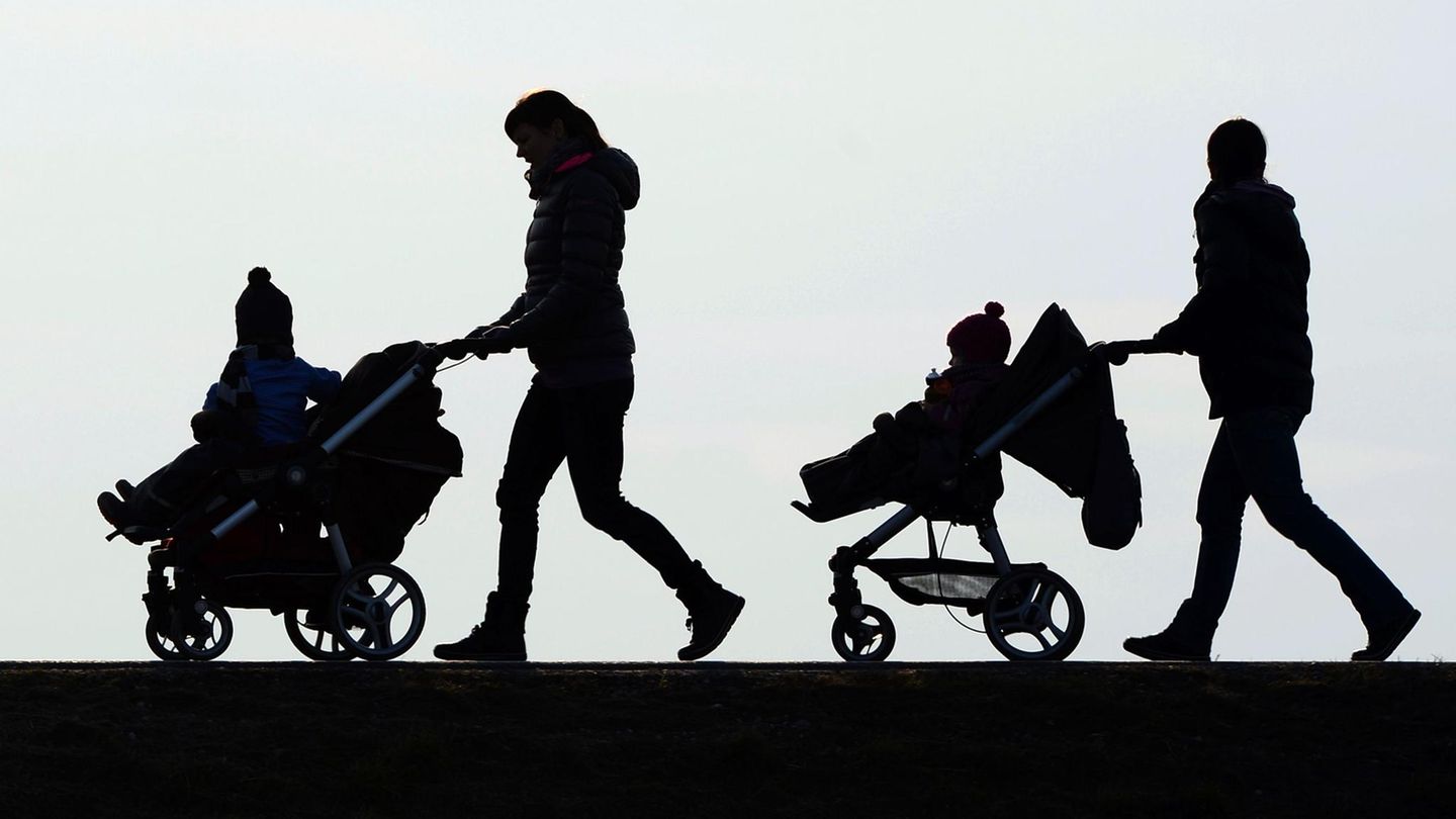Zwei Mütter schieben mit einem Kinderwagen ihre Kinder