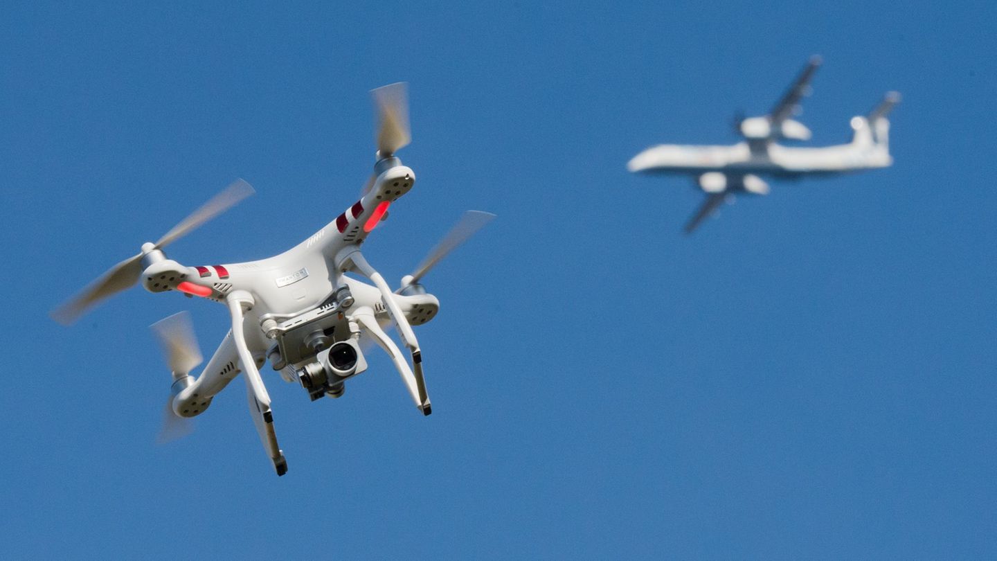 Eine private Drohne fliegt in weiter Entfernung von einem Flugzeug, das im Anflug auf den Flughafen Düsseldorf ist. (Symbolbild)