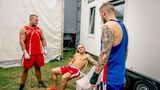 Pause in der Boxbude: Drei Kämpfer stehen und sitzen im Klappstuhl-Kreis und reden