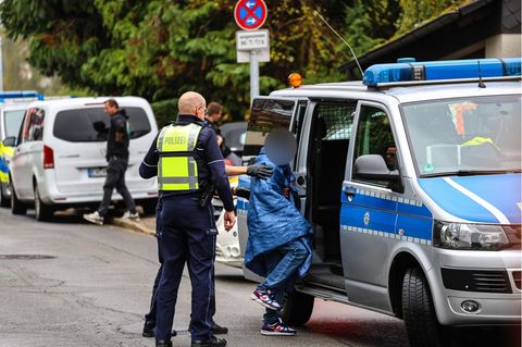 Ein Jugendlicher wird nach der Messerattacke auf Iris Stalzer in Herdecke in ein Polizeifahrzeug geführt