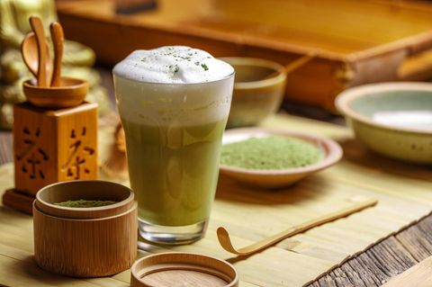 Matcha Latte im Glas auf einem Holztisch mit japanischem Geschirr