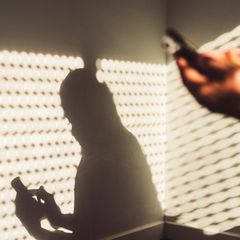 Handysucht: Eine junge Frau sitzt mit ihrem Handy zuhause