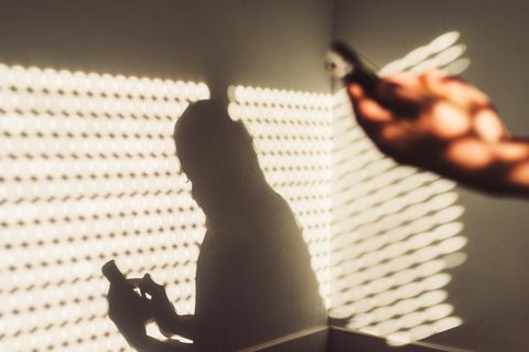 Handysucht: Eine junge Frau sitzt mit ihrem Handy zuhause
