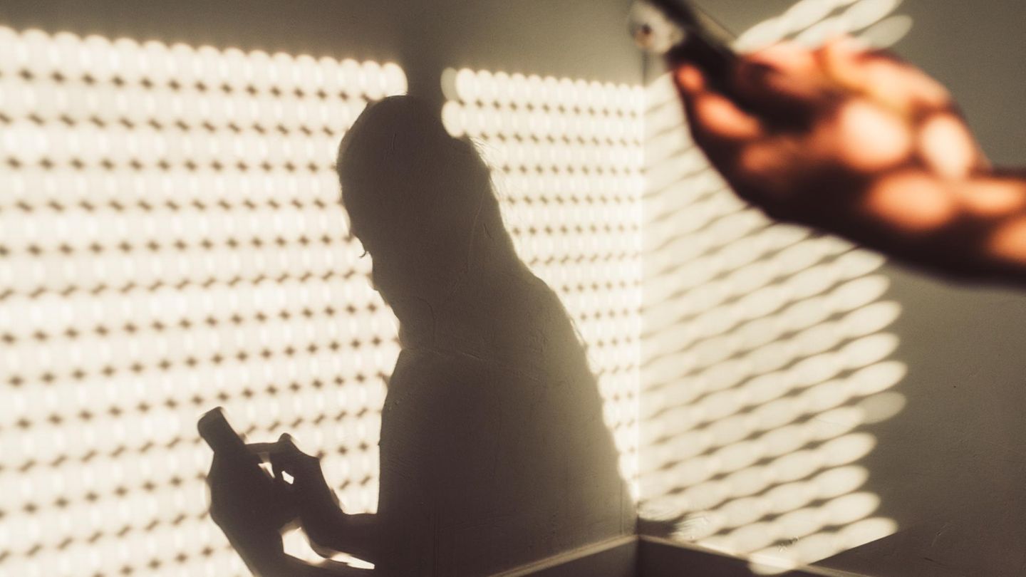 Handysucht: Eine junge Frau sitzt mit ihrem Handy zuhause