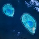 Wie Mikroben unter einem Mikroskop sehen diese beiden Koralleninseln im Baa-Atoll aus. Das Wasser dort ist zwischen 25 und 30 Grad warm. Immer. Beste Bedingungen für die unzähligen Korallentierchen, aus dessen Stützskelett letztlich die Riffe bestehen
