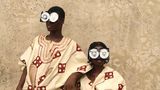 Zwei junge Menschen posieren vor einer rauen Wand, in reich bestickten Gewändern aus Aso Oke – jenem handgewebten Stoff aus Nigeria, der traditionell bei Zeremonien getragen wird. Ihre Gesichter sind größtenteils von futuristischen Brillen aus recycelten VHS-Kassetten verdeckt – eine witzige und prägnante Metapher für die Verwandlung veralteter Technik in ein neues Ritualobjekt und Werkzeug des kulturellen Ausdrucks