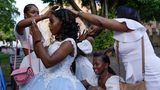 Freunde und Familie umsorgen eine 15-Jährige, die ihre "Quinceañera" feiert – ein traditionelles Fest zum 15. Geburtstag eines Mädchens in Lateinamerika. Es symbolisiert den Übergang von der Kindheit zum Erwachsenwerden und stellt die offizielle Einführung der jungen Frau in die Gesellschaft dar. Die Aufnahme entstand, als sich die junge Frau auf ihre Fotosession auf der Plaza Colón im Stadtteil Zona Colonial in Santo Domingo vorbereitete