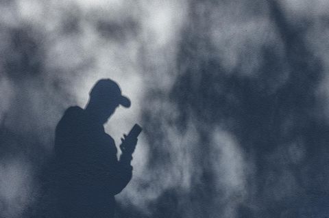 Ein nuzr als Schatten sichtbarer Mann nutzt ein iPhone