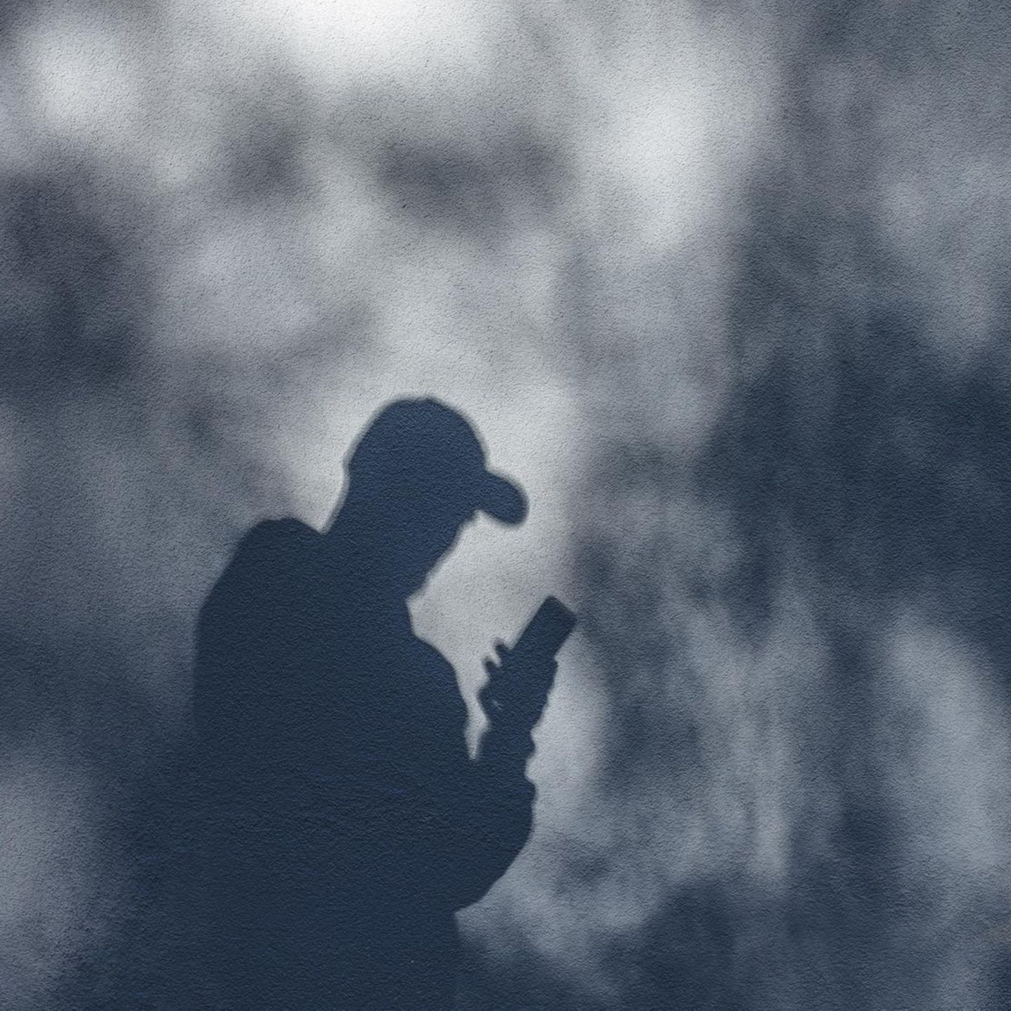 Ein nuzr als Schatten sichtbarer Mann nutzt ein iPhone