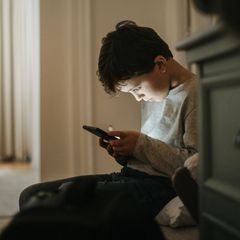 Smartphone, aber sicher: Ein Junge sitzt im Flur und starrt auf sein Handy