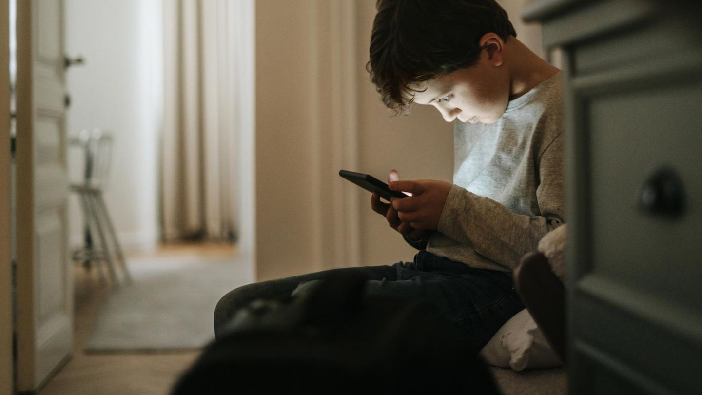 Smartphone, aber sicher: Ein Junge sitzt im Flur und starrt auf sein Handy