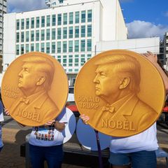 Demonstranten halten selbstgemachte Friedensnobel-Preismedaillen mit dem Bildnis von Donald Trump hoch