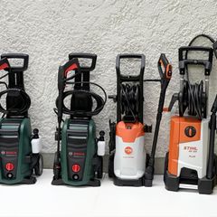 Sechs Hochdruckreiniger stehen vor einer Hauswand