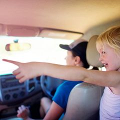 Kinder im Auto: Ein Mädchen zeigt aus dem Fenster