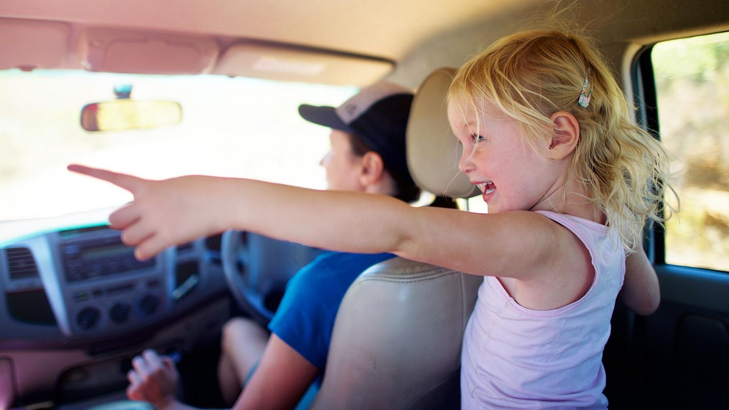 Kinder im Auto: Ein Mädchen zeigt aus dem Fenster