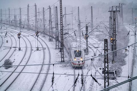 Ein ICE der Deutschen Bahn im fährt im Winter über verschneite Gleise