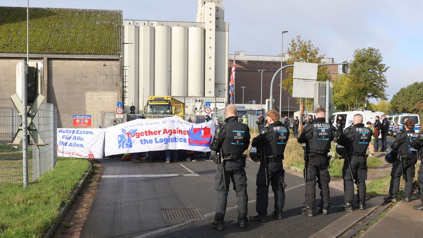 Mit einer Sitzblockade protestieren Aktivisten vor der Zufahrt eines Hafendienstleisters in Bremen-Walle. Foto: Christian Butt/d