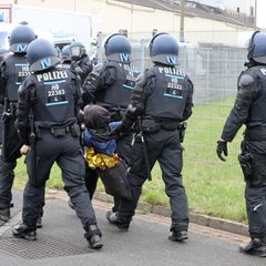 Weil sie ihre Vermummung nicht ablegen wollten, sind einige Protestierende weggetragen worden. Foto: Christian Butt/dpa