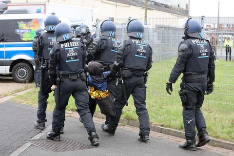Weil sie ihre Vermummung nicht ablegen wollten, sind einige Protestierende weggetragen worden. Foto: Christian Butt/dpa