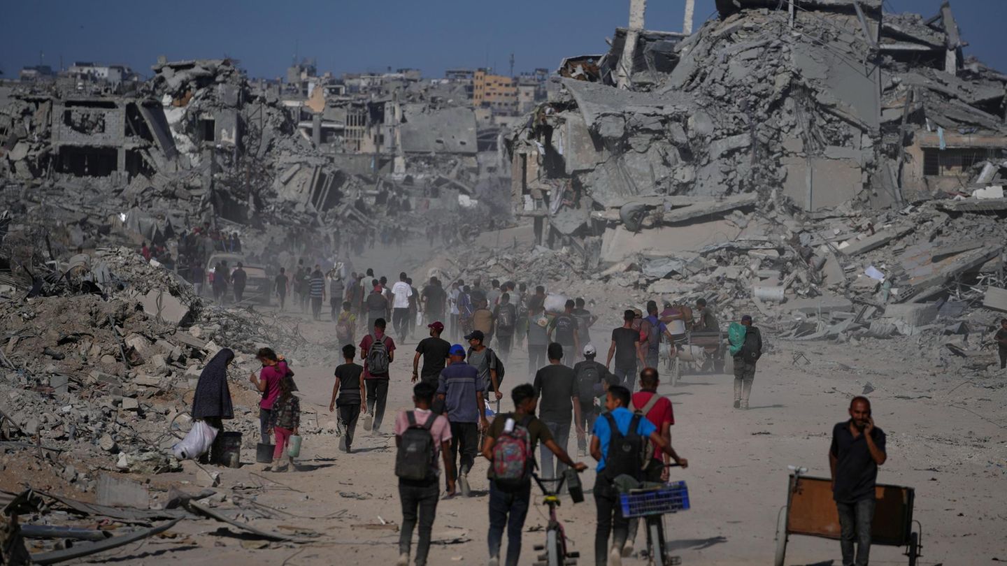 Palästinenser gehen an zerstörten Gebäuden vorbei, während sie in ihre Häuser im Zeitoun-Viertel von Gaza zurückkehren