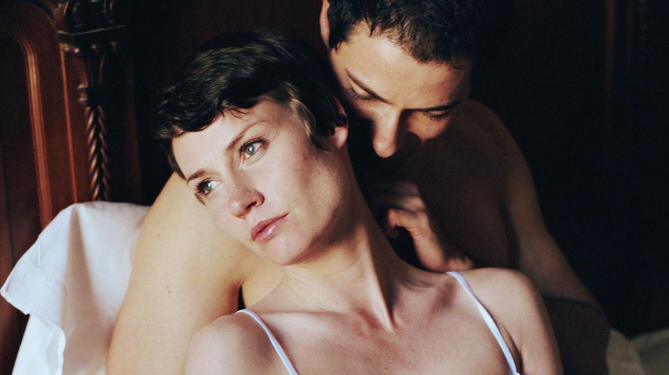 Ein Mann und eine Frau im Bett. Der Mann versucht sich zärtlich zu Nähern, doch die Frau sieht uninteressiert aus.