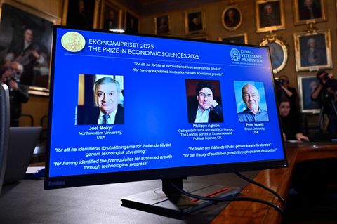 Ein Bildschirm bei der Verleihung des Nobelpreises für Wirtschaft zeigt Joel Mokyr, Philippe Aghion und Peter Howitt
