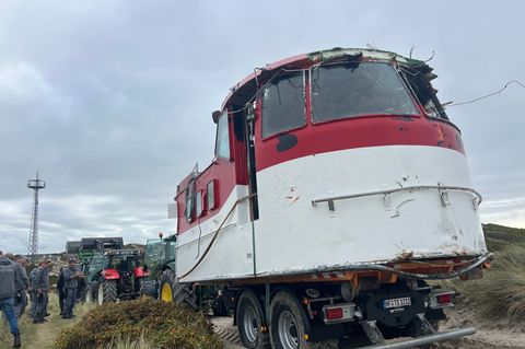 Mit mehreren Traktoren wurde der vor Sylt angespülte Aufbau eines ehemaligen Lotsenbootes hinter die Düne in Hörnum (Sylt) gezog