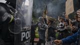Älterer Mann stellt sich mit Blumen in der Hand Polizisten entgegen