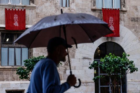 Ein Mann mit Regenschirm geht durch Valencia in Spanien