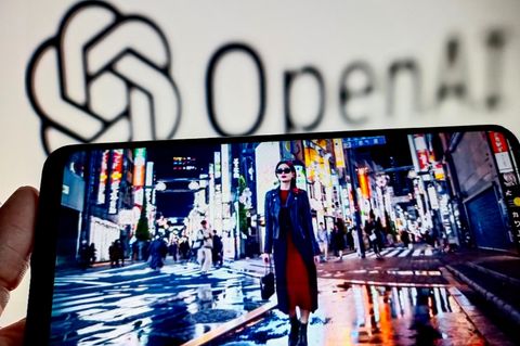 Ein Smartphone zeigt die Sora-App mit einem KI-Video vor dem Logo des ChatGPT-Anbieter OpenAI