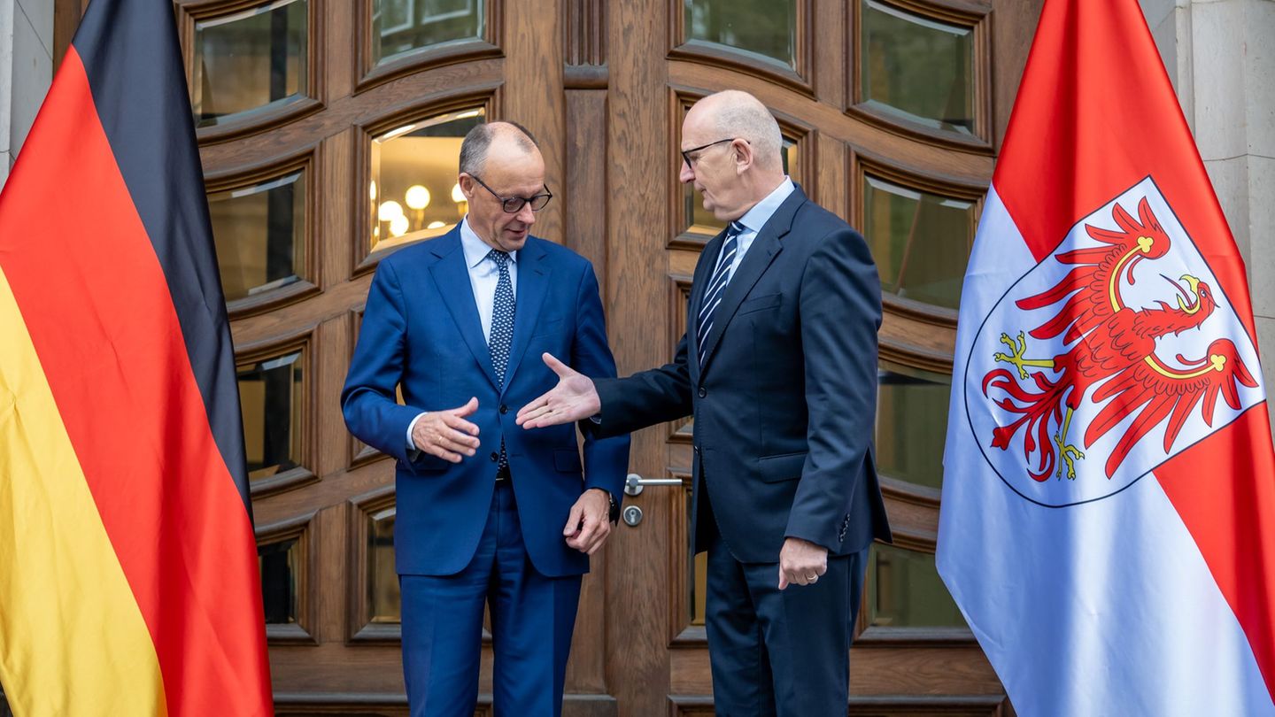 "Shake hands" zum Auftakt: Kanzler Merz (CDU) wird vom brandenburgischen Ministerpräsidenten Dietmar Woidke (SPD) empfangen. Es