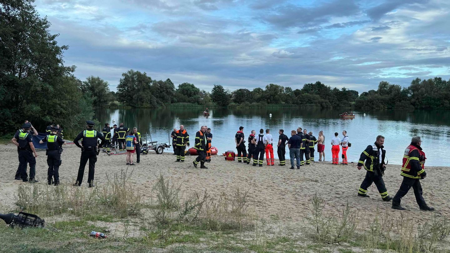 Polizisten und Feuerwehrleute stehen am See Hinterm Horn in Hamburg. (Archivbild) Foto: Sebastian Peters/NEWS5/dpa