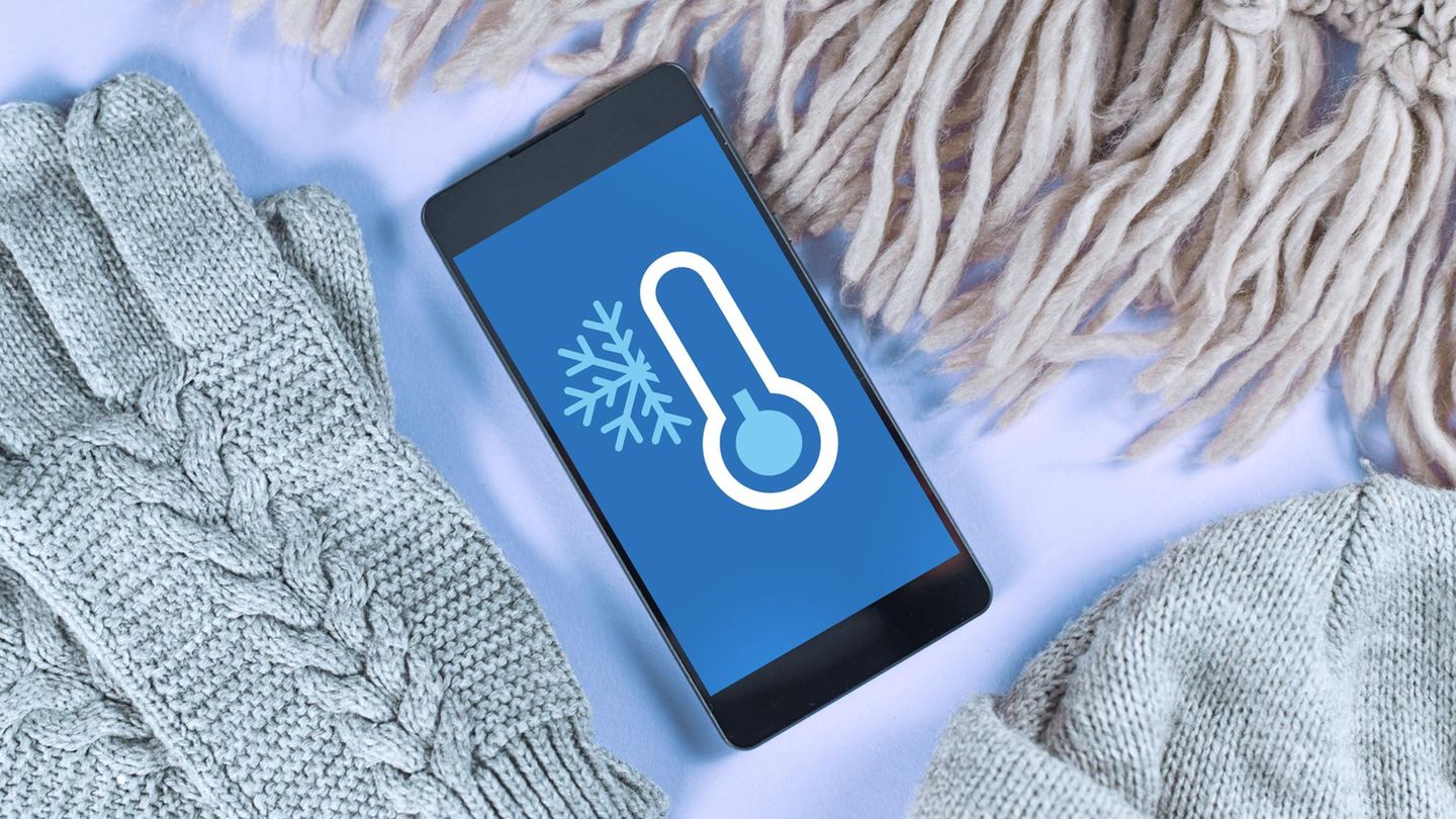 Handy vor Kälte schützen: Eine Frau macht auf einem schneebedeckten Berg ein Selfie von sich