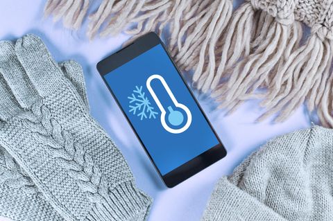 Handy vor Kälte schützen: Eine Frau macht auf einem schneebedeckten Berg ein Selfie von sich