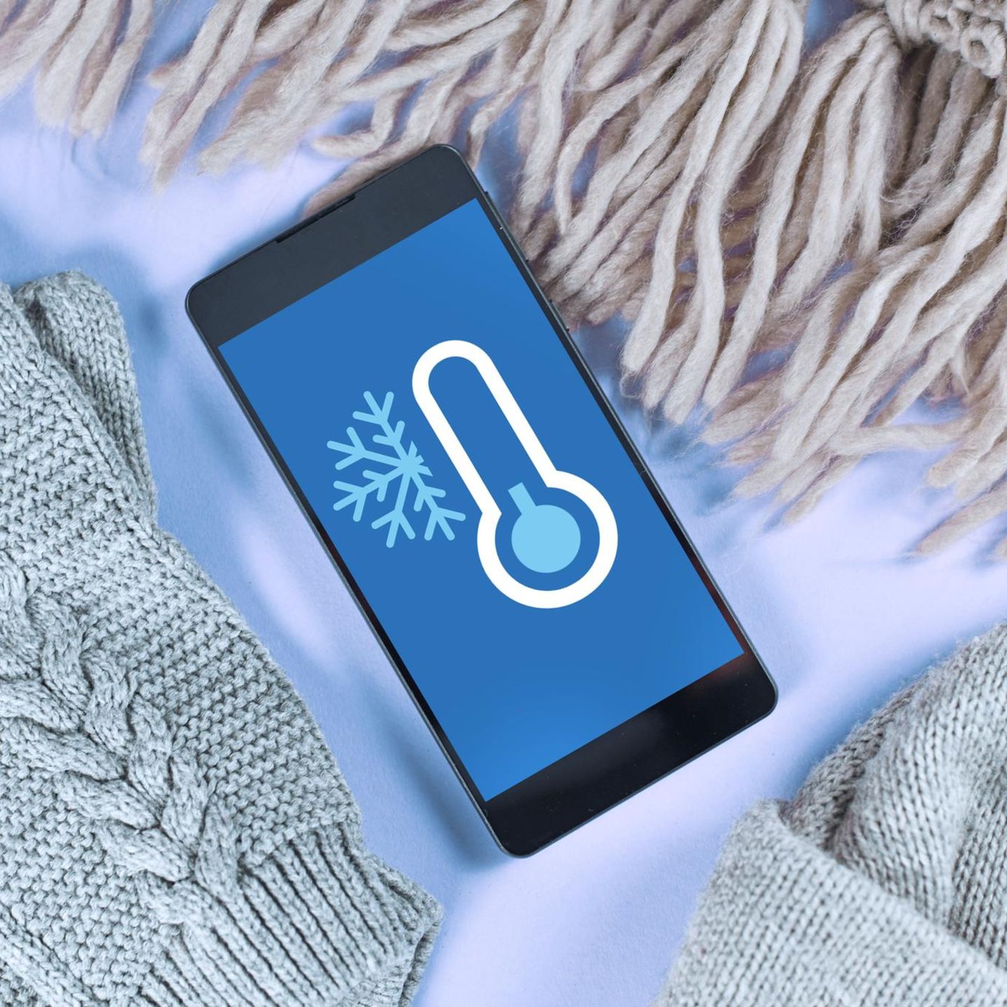 Handy vor Kälte schützen: Eine Frau macht auf einem schneebedeckten Berg ein Selfie von sich