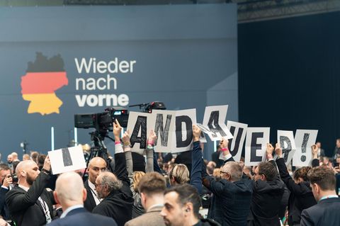 Demonstranten halten Schilder mit den Buchstaben des Wortes Brandmauer hoch