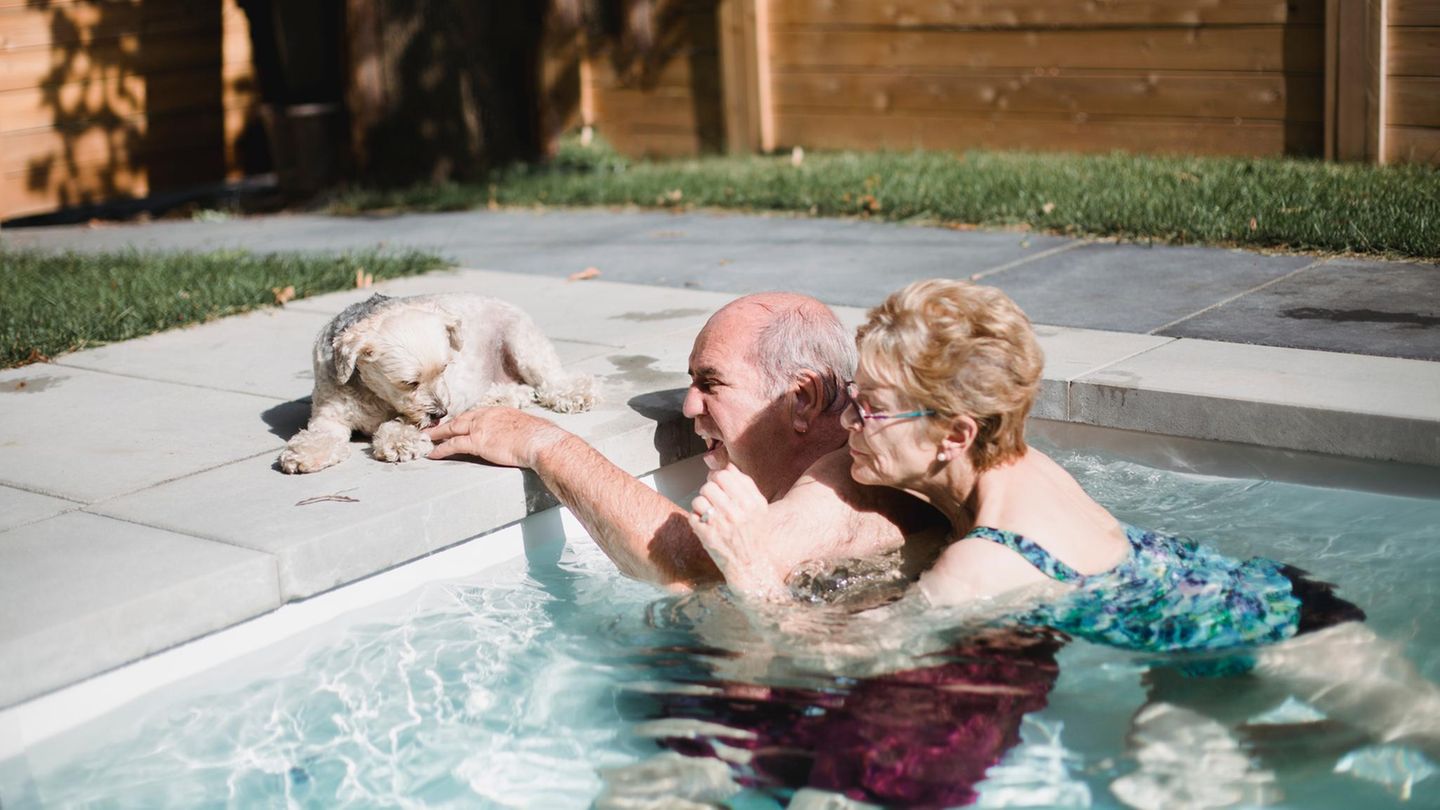 Eine Frau hält sich im Pool an ihrem Mann fest