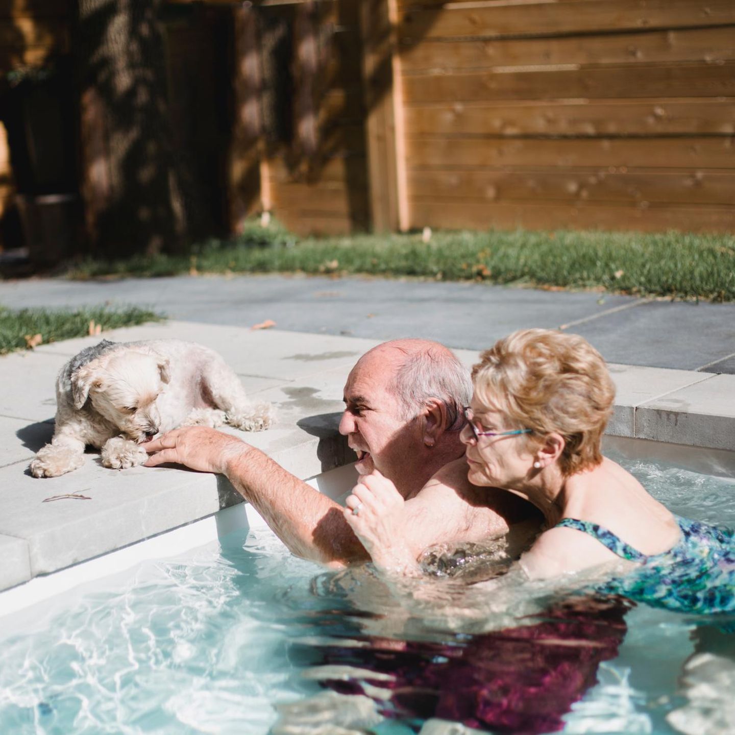 Eine Frau hält sich im Pool an ihrem Mann fest