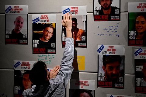 Ein Mann klebt HOME Aufkleber auf die Plakate der Geiseln: Sie sind nun zuhause