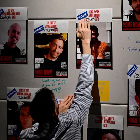 Ein Mann klebt HOME Aufkleber auf die Plakate der Geiseln: Sie sind nun zuhause