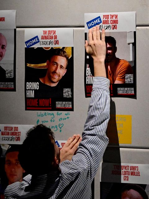 Ein Mann klebt HOME Aufkleber auf die Plakate der Geiseln: Sie sind nun zuhause