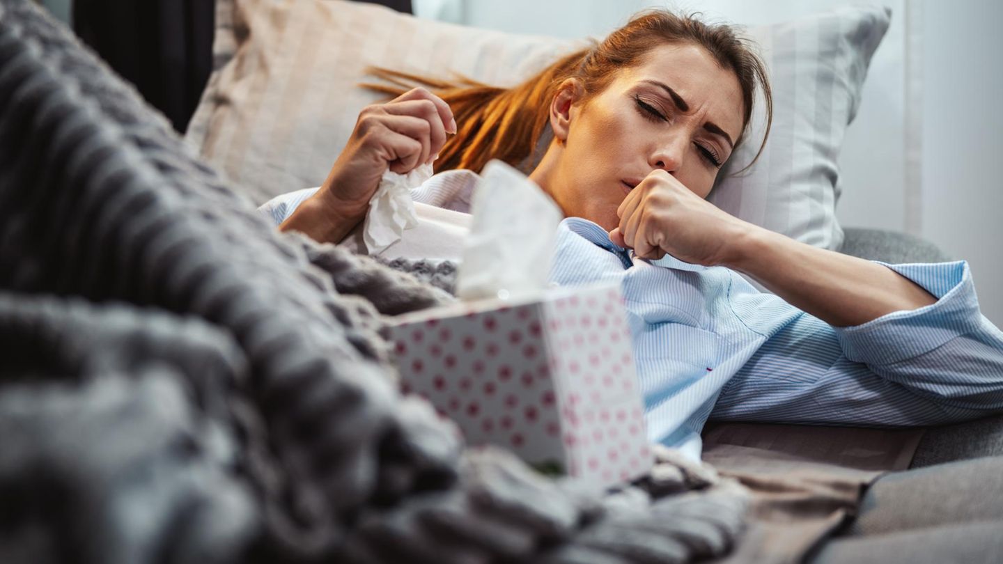 Husten: Frau liegt krank auf dem Sofa