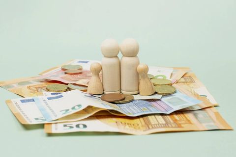 Kindergeld Symbolbild: Spielfiguren (2 große, 2 kleine) stehen auf Euroscheinen und -Münzen