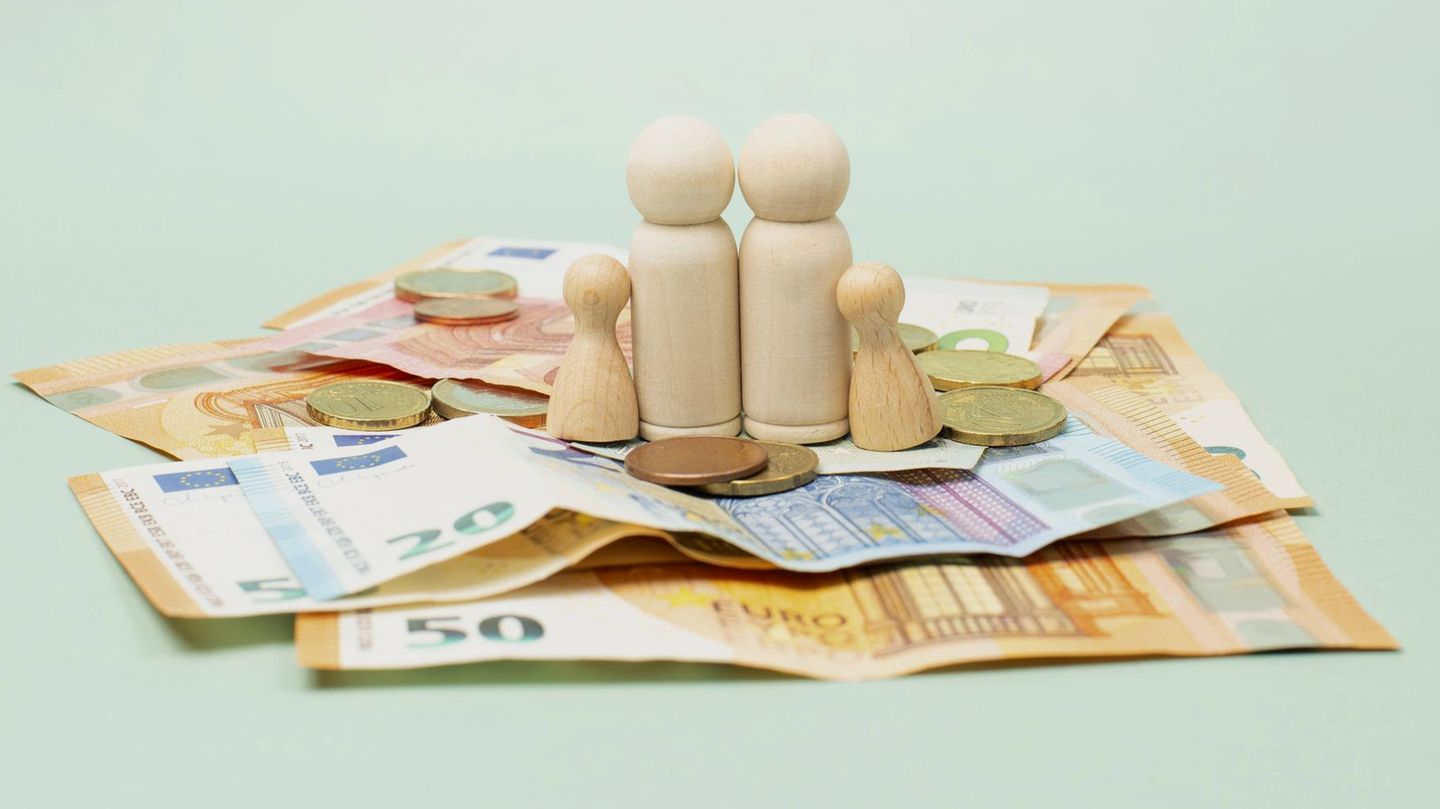Kindergeld Symbolbild: Spielfiguren (2 große, 2 kleine) stehen auf Euroscheinen und -Münzen