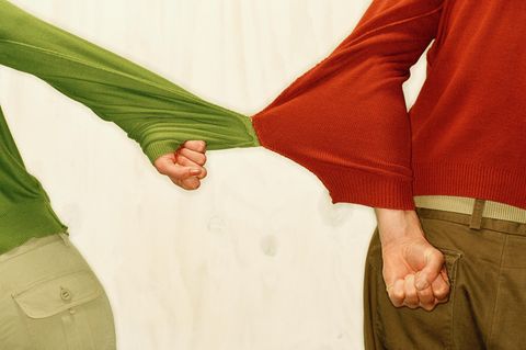 Ein Paar hängt mit den Ärmeln seiner Pullis zusammen, sie versuchen eine trennung Ein Paar hängt mit den Ärmeln seiner Pullis zusammen, sie versuchen eine trennung