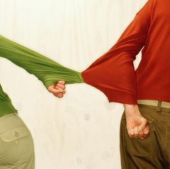 Ein Paar hängt mit den Ärmeln seiner Pullis zusammen, sie versuchen eine trennung